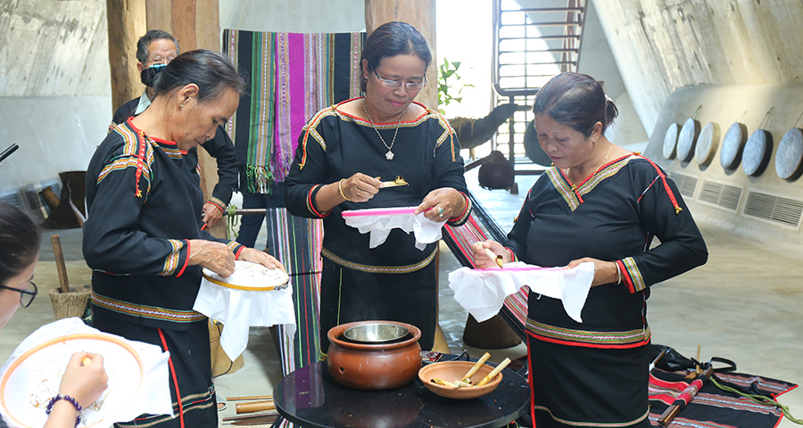 Nghệ nhân H’Yam Bkrông (giữa) và các nghệ nhân dệt thổ cẩm giao lưu vẽ batik